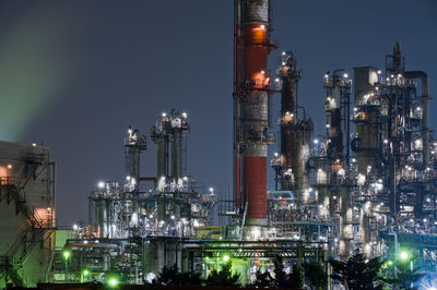 Illuminated factory against sky at night