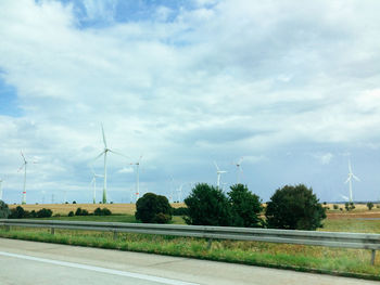 Wind turbines on field against cloudy sky