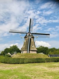 Traditional windmill on field against sky