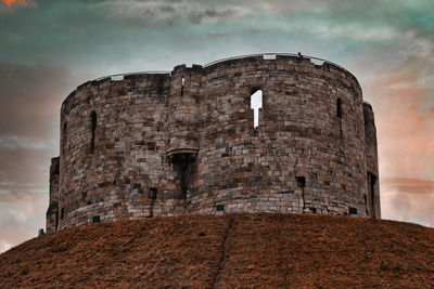 Low angle view of fort against cloudy sky