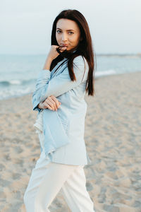 Portrait of beautiful young woman standing on beach