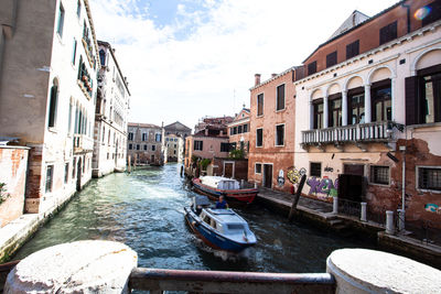 Canal amidst buildings in city against sky