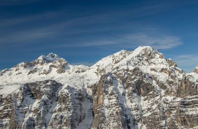 Low angle view of snowcapped mountain against blue sky