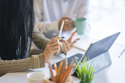 Midsection of woman holding paper with text on table