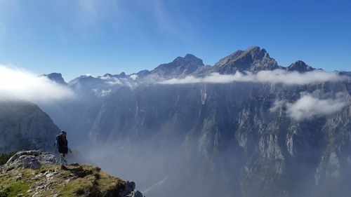 Side view of woman standing on mountain against sky