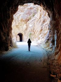 Rear view of woman standing in cave