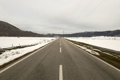 Road leading towards mountains against sky