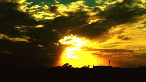 Silhouette landscape against dramatic sky during sunset