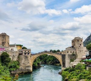 Arch bridge over river against cloudy sky