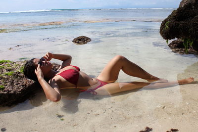 Young woman lying on shore at beach