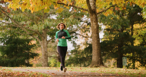 Full length of young woman jogging in park during autumn
