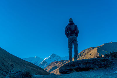 Rear view of man on mountain against clear blue sky