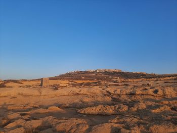 Scenic view of desert against clear blue sky