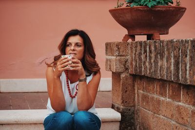 Full length of woman sitting against wall