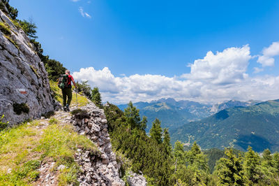 Rear view of man looking at mountains against sky