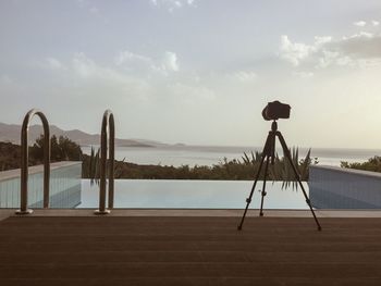 Camera on tripod at poolside with beach in background