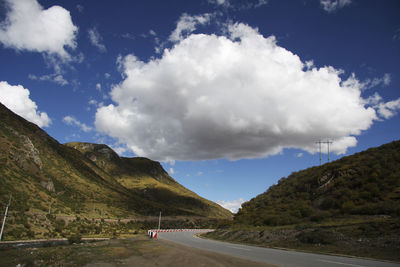 Scenic view of road by mountain against sky