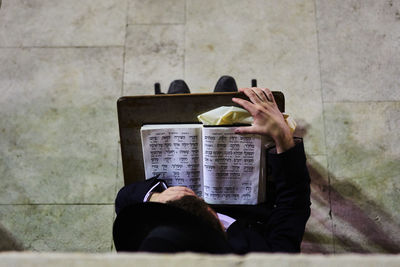 Man holding paper while sitting against wall