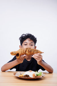 Portrait of woman holding food on table against white background