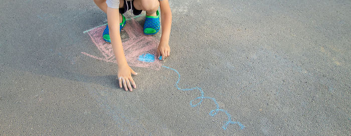 Low section view of boy drawing with chalk on road