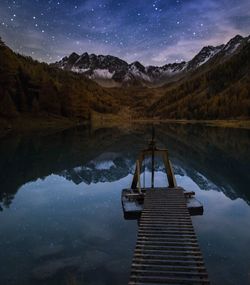 Scenic view of lake and mountains against sky at night