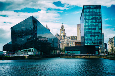 Buildings by river against sky