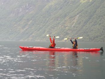 Men on boat in lake against mountain