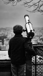 Rear view of boy standing by coin-operated binoculars