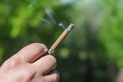 Close-up of hand holding cigarette