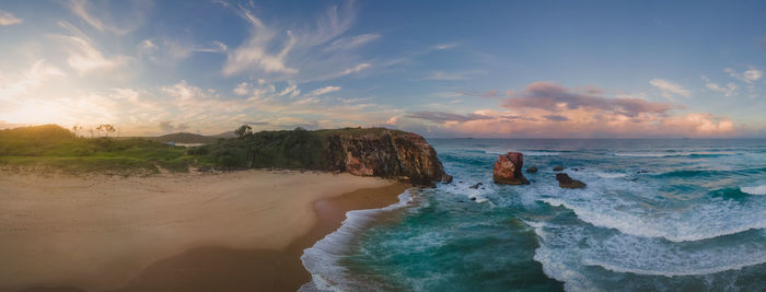 Aerial panorama of coastal landscape with beach and rock formation during moody sunset