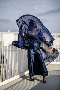 Full length of woman wearing navy blue dress while standing by railing