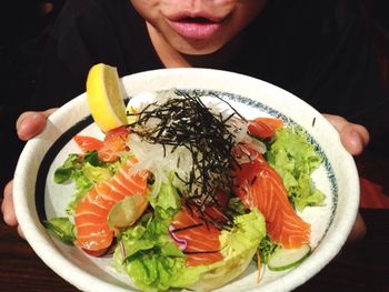 High angle midsection of man holding sashimi with cabbage in plate at home