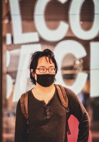 Portrait of young woman standing against wall