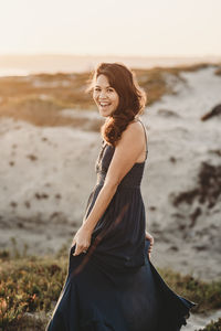 Laughing mid-40's beauty with long dark hair on sand dune