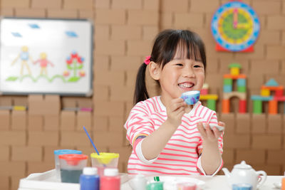 Portrait of happy girl holding ice cream on table