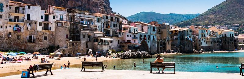 People sitting on table by chairs against clear sky