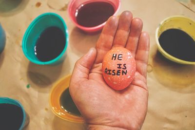 Cropped hand of man holding easter egg with text at table