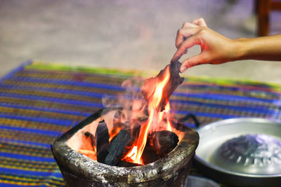 Cropped hand holding coal in fire pit