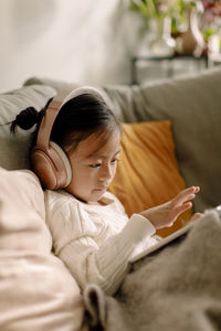 Girl on sofa watching movie through digital tablet at home