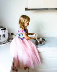 Little girl in elegant dress sitting on a table in the kitchen