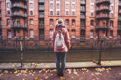 Rear view of woman standing by railing in city