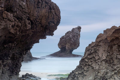 Rock formations by sea against sky