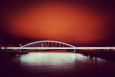 Bridge over river against sky at night