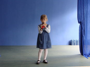 Full length portrait of girl standing against blue sky