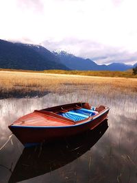 Boat moored in lake against sky