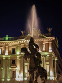 Low angle view of fountain in city against sky at night