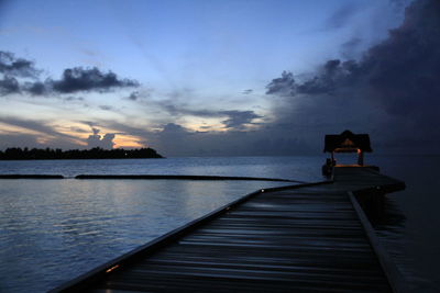 Pier on sea against sky at sunset