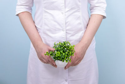 Midsection of woman holding ice cream against white background