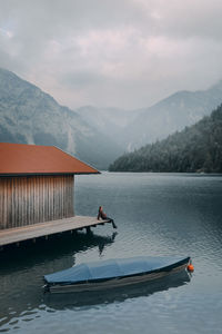 Man sitting on pier over lake