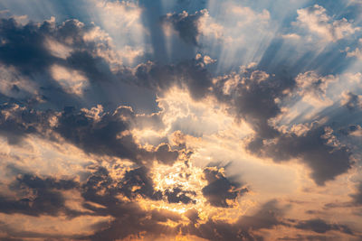 Sun rays cutting the clouds and passing through it with the sun in centre, covered by the clouds.